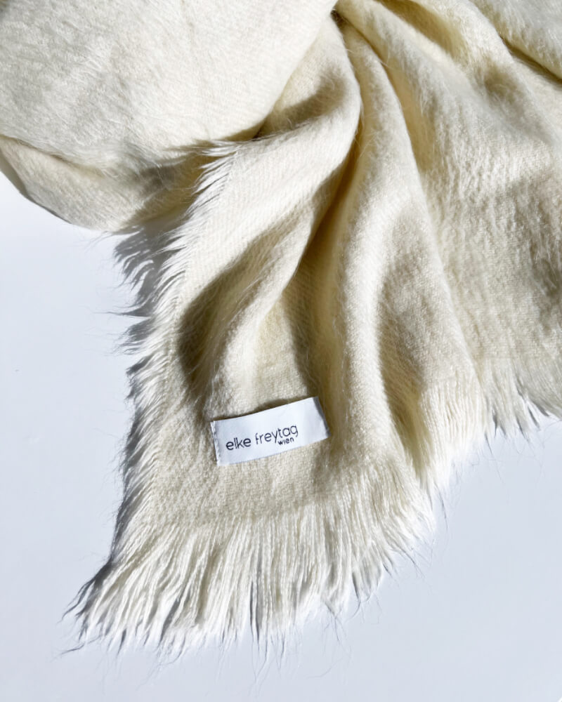 Der winterweisse Kuschelschal ist der Blickfang für jedes Herbst und Winteroutfit. Das Material besteht aus Designer leftover fabric 100% Viscose. Gewaschen wird der Schal mit 30 Grad im Wollprogramm und es ist nicht für den Trockner geeignet. Erwerben kannst du das Designer Stück bei elke freytag wien in der Lindengasse 14, im siebten Bezirk und im Online Store. Alle Designs der Marke elke freytag sind fair, nachhaltig und aus hochwertigen Materialen produziert. Der Schal kostet € 58,00 und trägt das Prädikat Handmade in WIEN